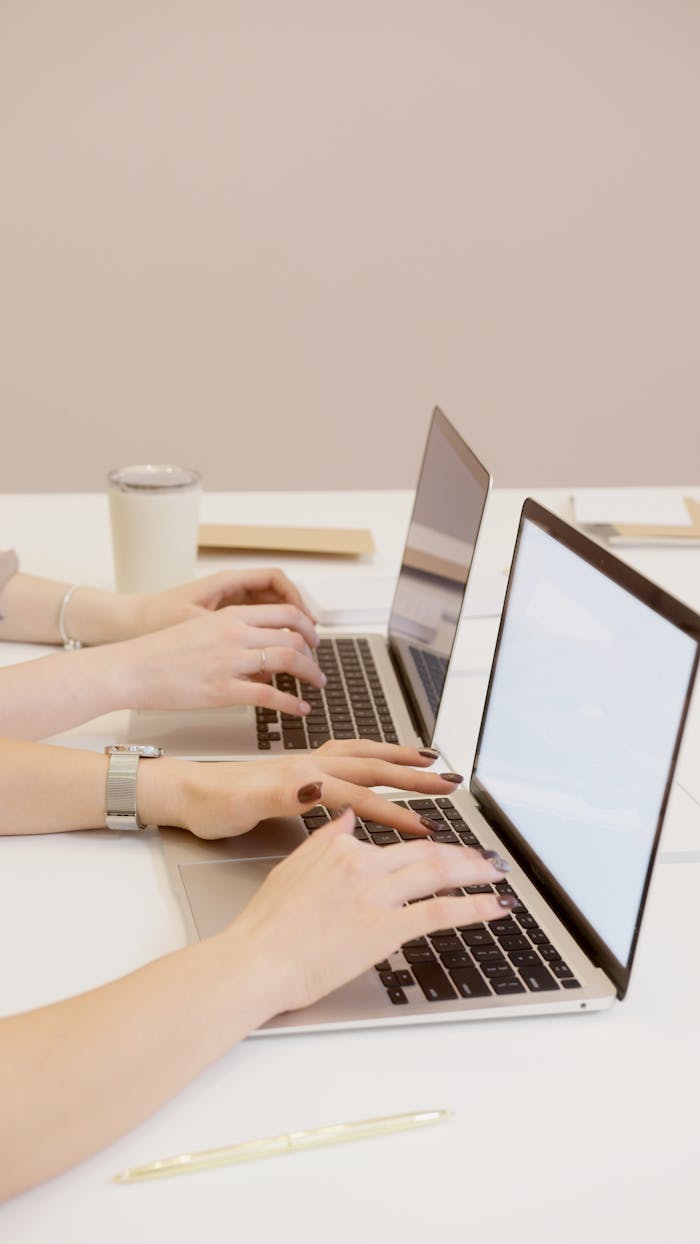 Home Two people typing on laptops in an office setting, emphasizing teamwork and productivity.